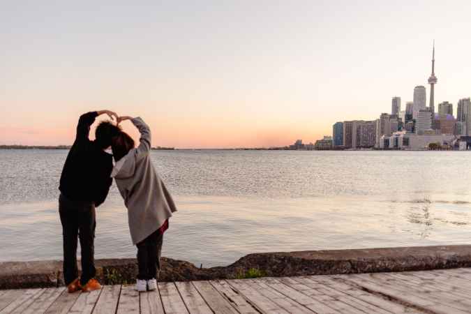 faceless couple forming heart with hands and enjoying toronto view Canada